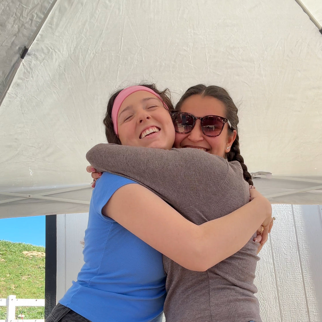 Two people hugging under a white canopy with a scenic background